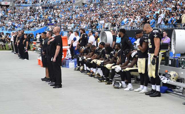 Jogadores do New Orleans Saints sentados durante o hino nacional