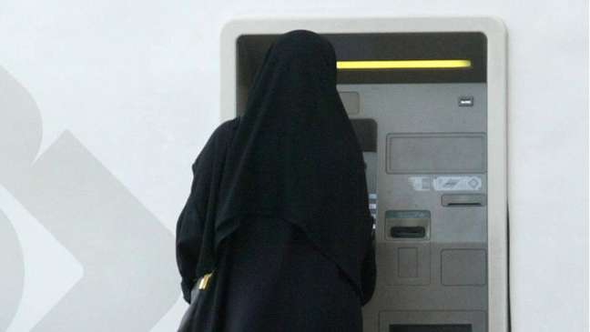 Mulher retira dinheiro em caixa automático na Arábia Saudita