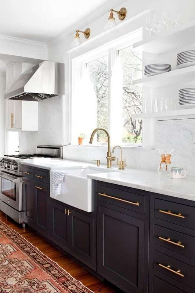 10. Sofisticada cozinha preta e branca com armário de cozinha preto e detalhes em dourado.
