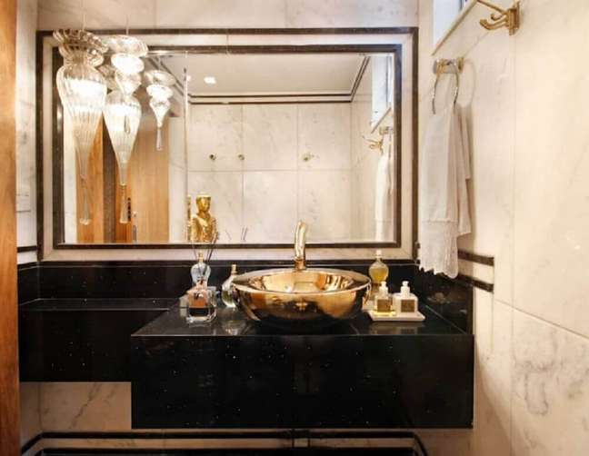 35. Banheiro sofisticado com bancada preta e cuba dourada