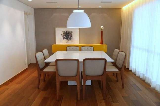 21. Sala de jantar decorada com piso de madeira e buffet amarelo