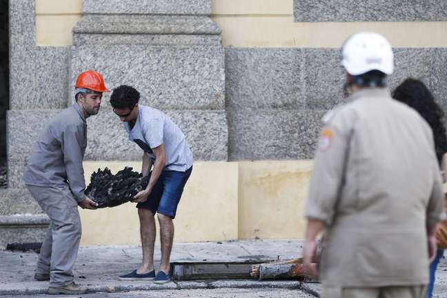 Pesquisadores e funcionários retiram peças dos escombros do Museu Nacional após incêndio