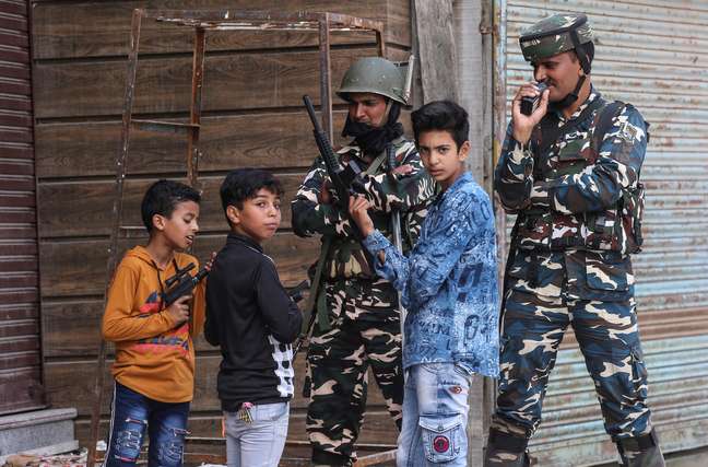 Crianças brincam com armas de brinquedo perto de membros das forças de segurança da Índia, na Caxemira
13/08/2019 REUTERS/Danish Ismail 