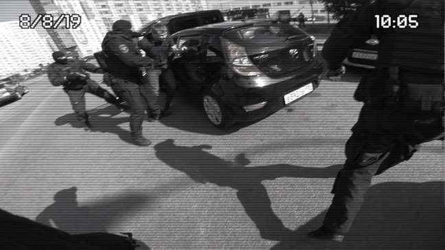 Amigo de Sergio é retirado do carro por atores vestidos como policiais