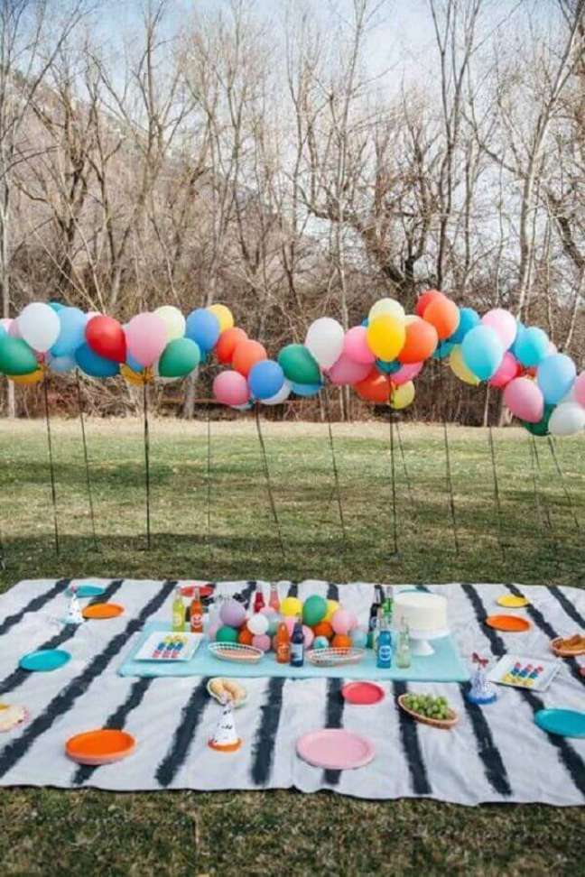 18. Arranjo de balões e toalha listrada para festa piquenique com pratos coloridos – Foto: Ideias Decor