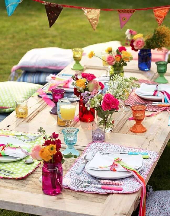 42. Almofadas e vasinhos coloridos de flor para decoração simples de festa piquenique – Foto: Pinterest