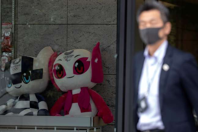 Homem usa máscara ao passar por mascotes da Olimpíada e Paralimpíada de Tóquio. REUTERS/Athit Perawongmetha