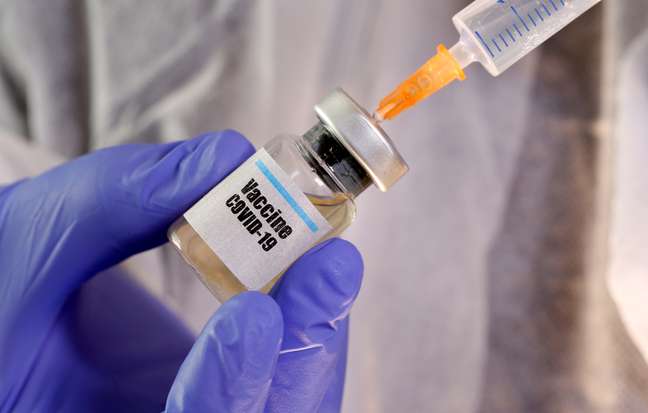 Pessoa manipula frasco com etiqueta nomeando vacina contra covid-19