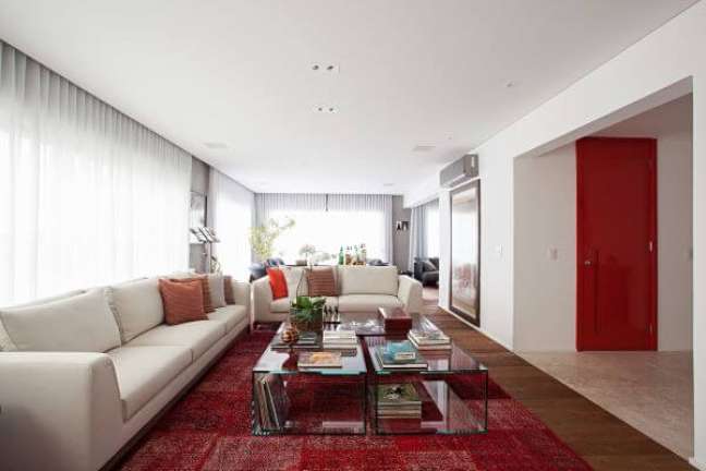 87. Sala grande decorada com tons de bege e vermelho com mesa de centro de vidro – Projeto Korman Arquitetos