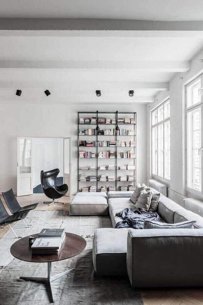 31. Poltrona giratória preta para sala grande decorada com sofá modular e estante de livros – Foto Apartment Therapy
