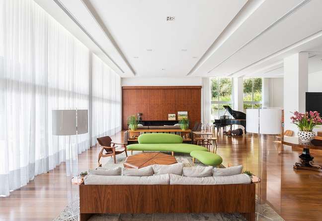 51. Sala grande decorada com criatividade e sofá verde e móveis de madeira – Projeto Leonardo Muller