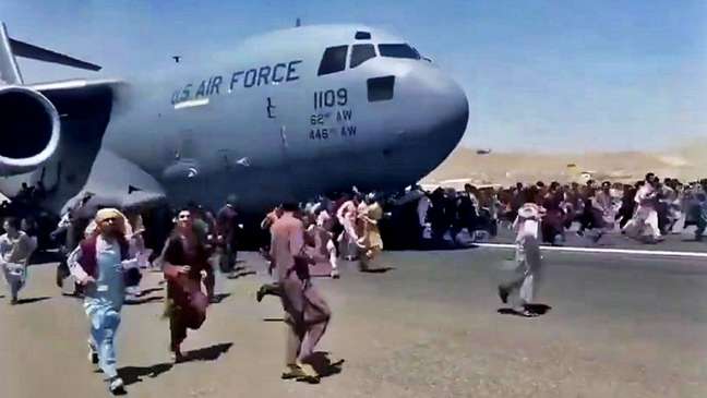 Pessoas correm na pista do aeroporto de Cabul tentando embarcar em um avião da Força Aérea dos Estados Unidos