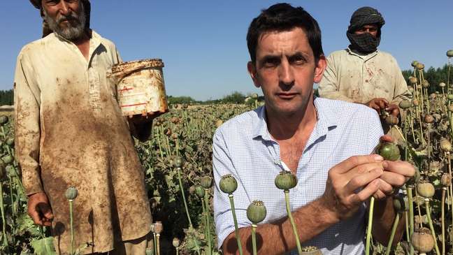 O repórter da BBC Justin Rowlatt em um campo de papoula no Afeganistão, em foto de arquivo; produção de heroína no país é improvisada, e não em laboratórios bem equipados