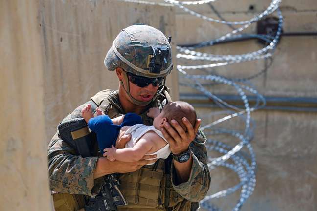 Soldado com criança afegã próximo ao aeroporto de Cabul, no Afeganistão