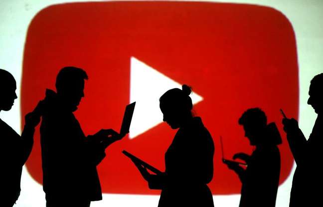 Silhuetas de usu&aacute;rios de dispositivos m&oacute;veis com logotipo do Youtube ao fundo. 28/3/2018.  REUTERS/Dado Ruvic