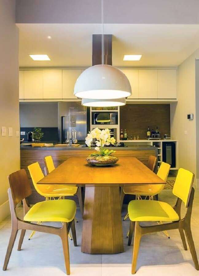 12. Cadeiras de madeira amarelas para decoração de sala de jantar colorida integrada com a cozinha – Foto: Archtrends