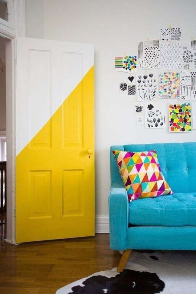 35. Decoração simples para sala colorida com sofá azul e porta meia pintada – Foto: OkChicas