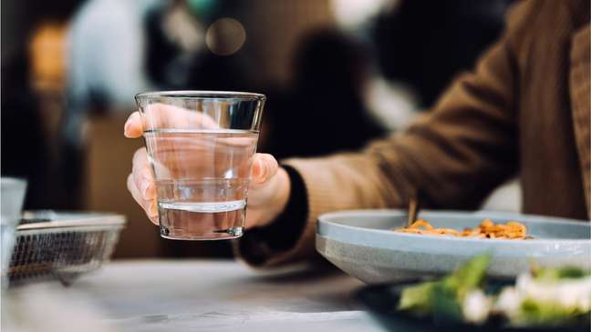 Mulher segurando copo de água durante a refeição