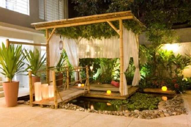 15. Pergolado de bambu para jardim com mini lago e cortinas brancas – Foto Casa e Construção
