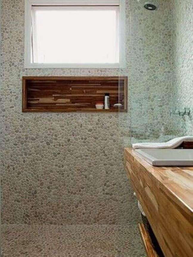 58. Revestimento de pedra para decoração de banheiro com nicho de madeira no box – Foto: Dicas Decor