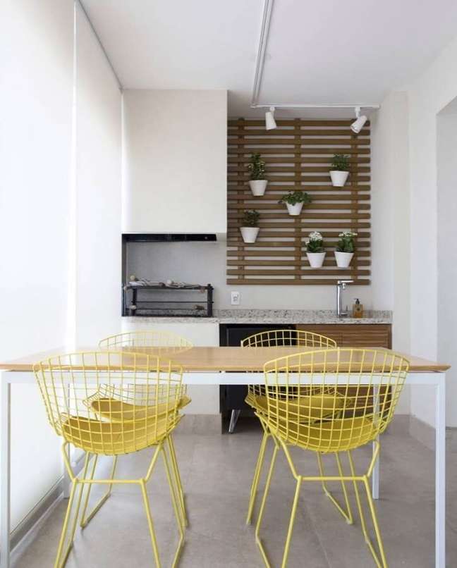 43. Decoração clean para varanda gourmet com churrasqueira e cadeiras amarelas – Foto: Decor Fácil