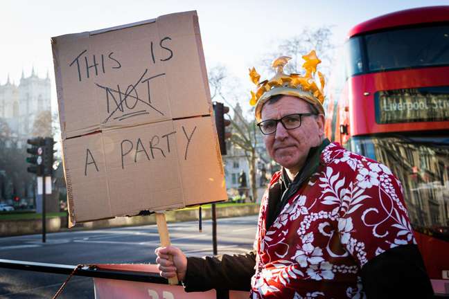 Manifestante mostra cartaz que diz: Isto (não) é uma festa