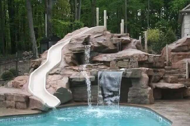 41. As pedras para cascata de piscina foram alinhadas em conjunto com o escorregador. Fonte Pool Piscina