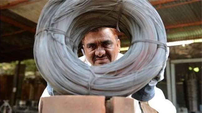 Niyazahmed Shaikh examina cuidadosamente rolos de fios produzidos com sucata de tiras de aço na sua fábrica na Índia