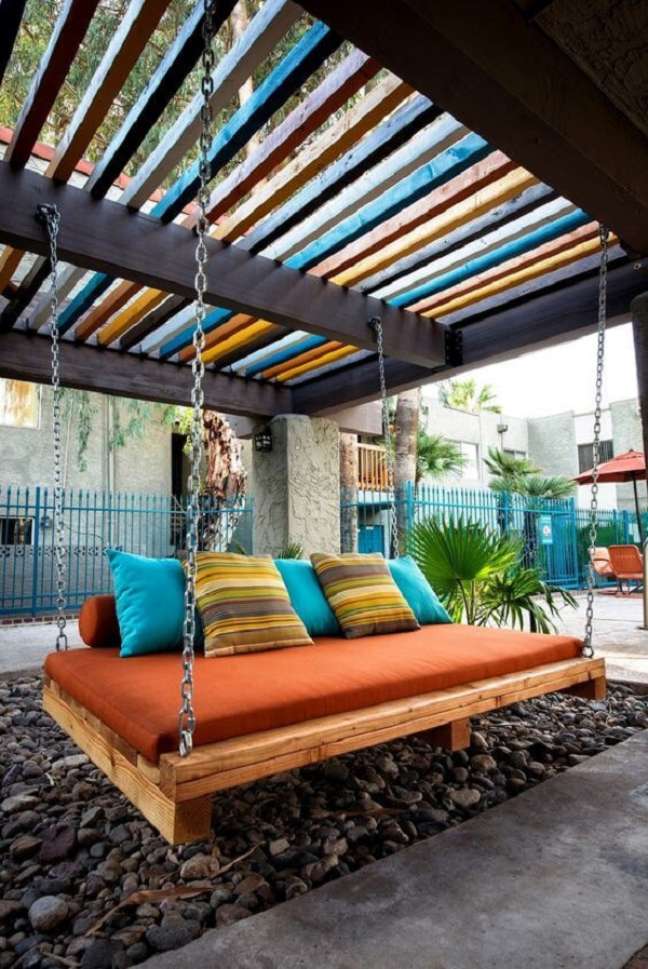 10. Pergolado de ferro e madeira com almofadas coloridas no sofá suspenso – Foto Happynest