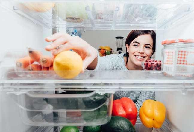 Mulher utilizando o refrigerador – Foto: Shutterstock