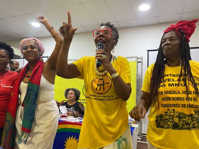 Imagem mostra membros do Movimento Negro Unificado com camisetas amarelas e segurando microfone