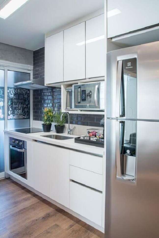 27. Decoração com revestimento preto e armário de cozinha pequeno planejado branco – Foto: Casa de Valentina