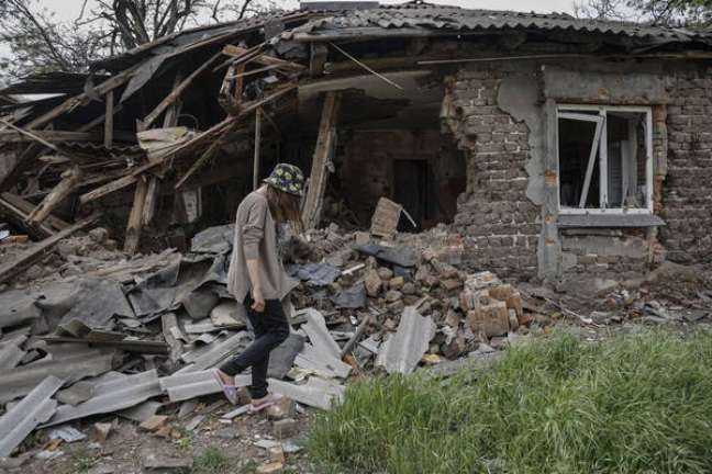 Uma mulher ucraniana na frente de uma residência destruída