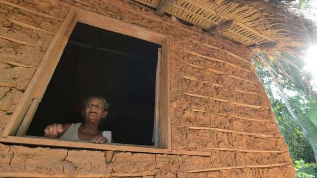 Foto de mulher quilombola na janela de uma casa.