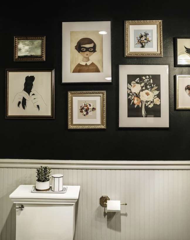 Banheiro com uma parede repleta de quadros.