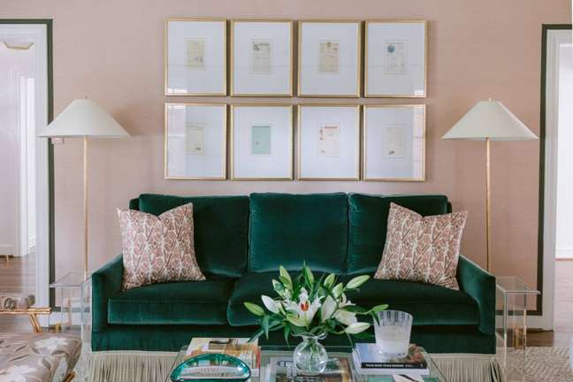 Sala de estar com parede rosa e sofá verde esmeralda