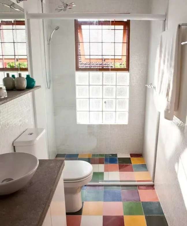 Moderna kopalnica s tlemi iz večbarvnih ploščic in toaletno mizico s kamnitimi pulti