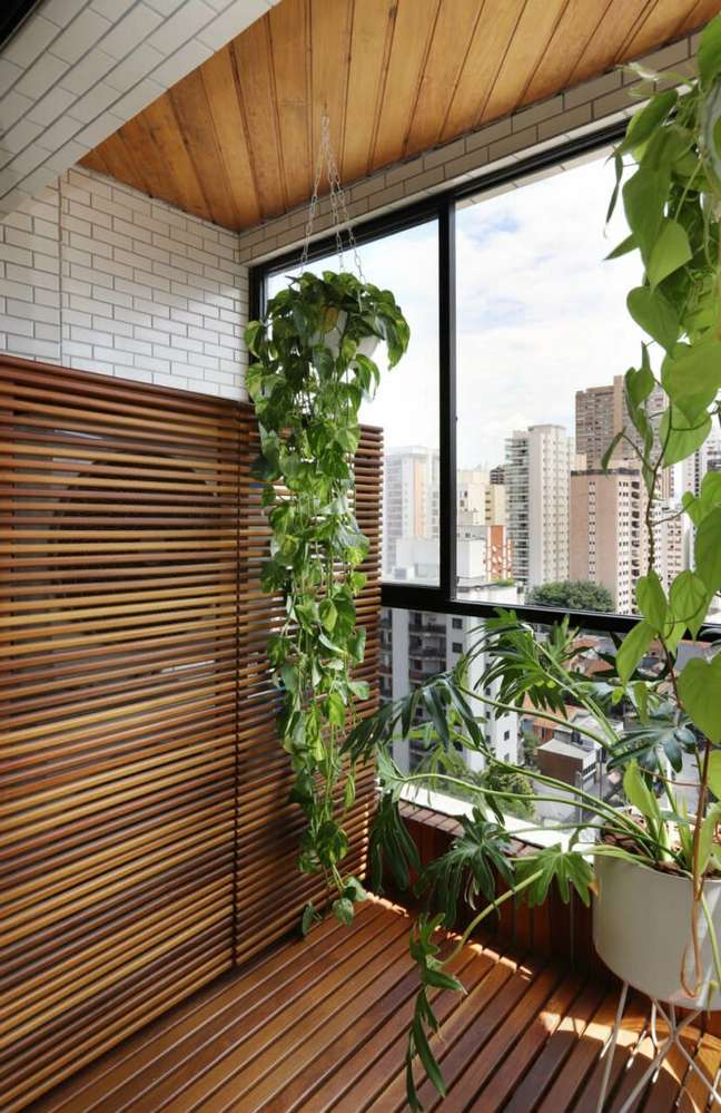 On the balcony of Flávia Lauzana's apartment, the wooden panel hides the air conditioning condenser.  On the floor, the bridge corrects irregularities.  Project by Flavia Lauzana.  Flavia Lauzana's project