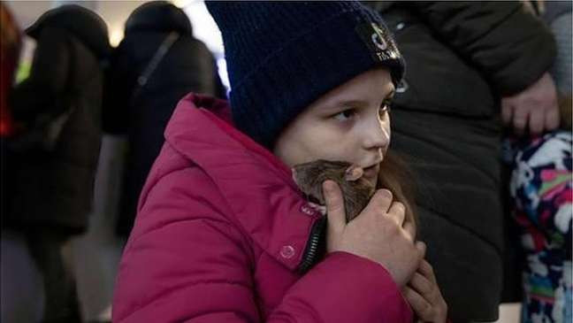 Menina ucraniana acarinha seu pet na estação de trem de Varsóvia, na Polônia. Pesquisas indicam que crianças consideram seus animais de estimação entre criaturas mais importantes das suas vidas