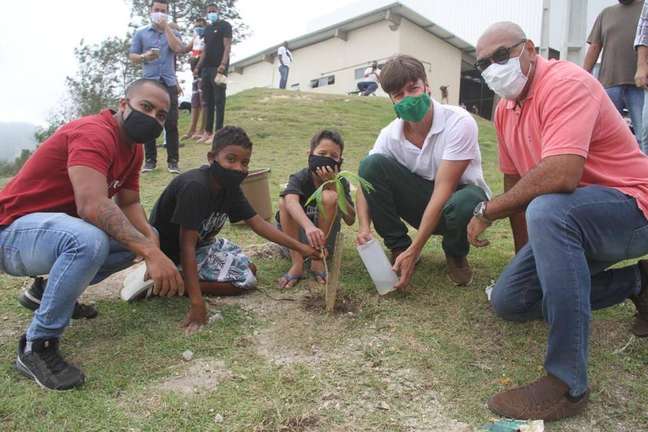O secretário Luciano Paez (de máscara verde) participa plantação de árvores no Caramujo, comunidade escolhida para projeto piloto de neutralização de carbono.