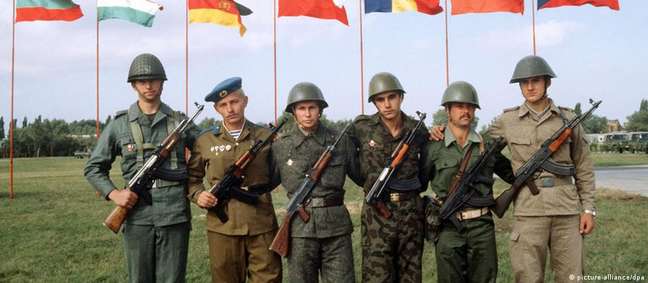 Soldados diante das bandeiras dos sete países signatários do Pacto de Varsóvia