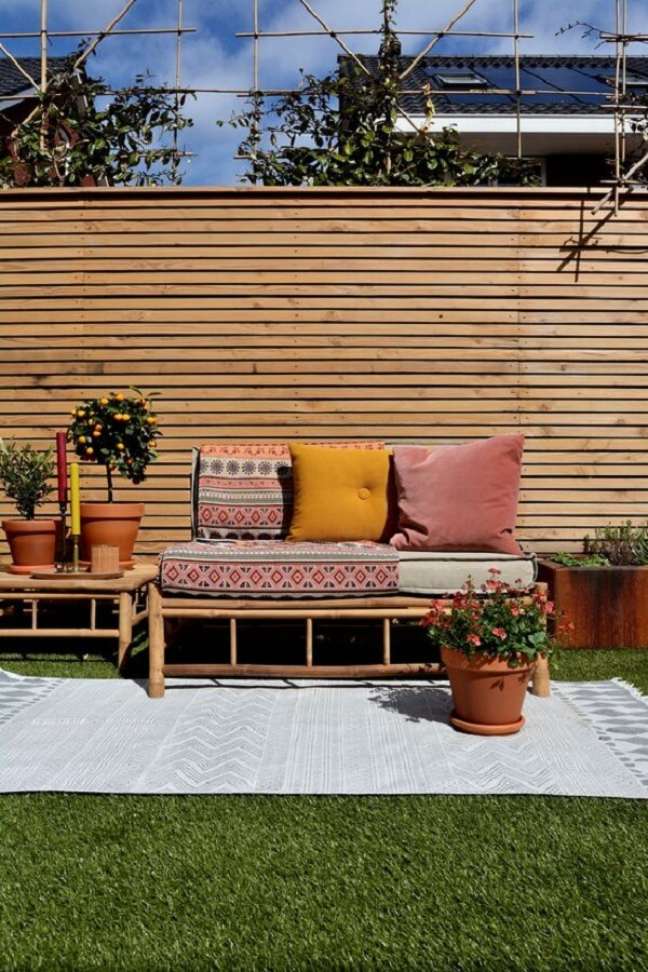16. Área externa com tapete, vasos de plantas e sofá de bambu. Fonte: Exotan