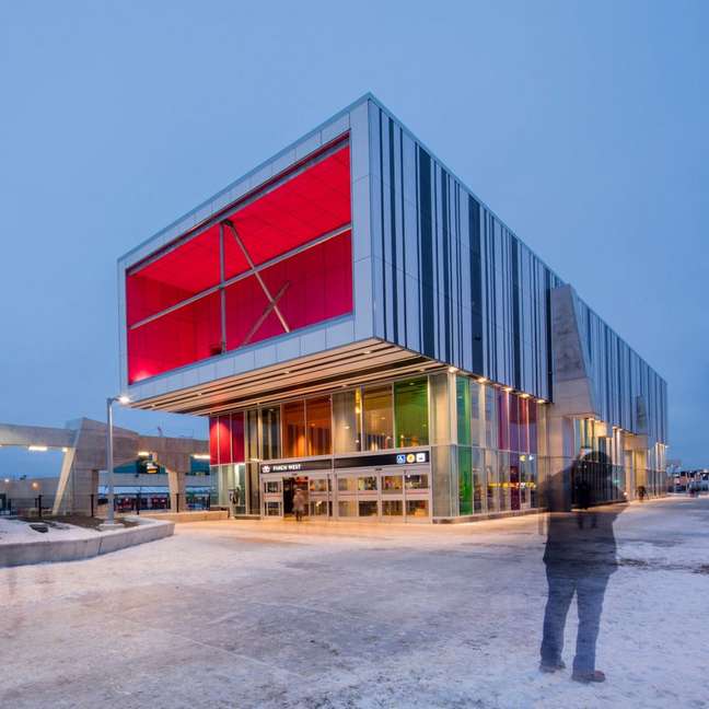 Above ground station with red, green and yellow colored façade, which stands out in the landscape.