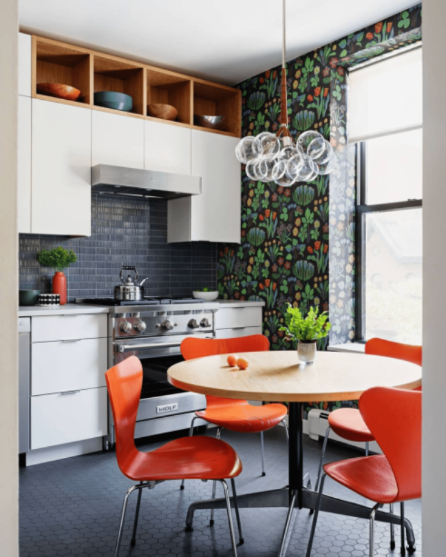 Wallpaper prints attract visual interest.  Additional focal points throughout the room - such as brightly colored chairs, a bright backsplash, a hanging pendant light, and honeycomb tile floors - create the feel of a spacious room.