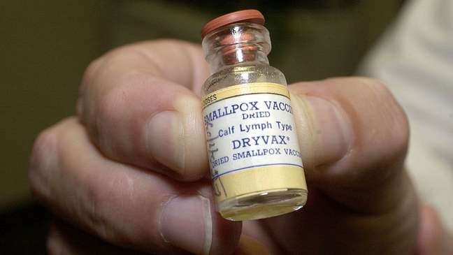 Mão segurando frasco de vacina contra varíola