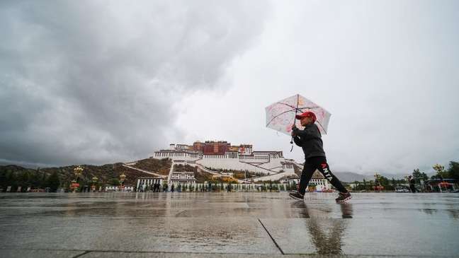 Criança caminha com guarda-chuva