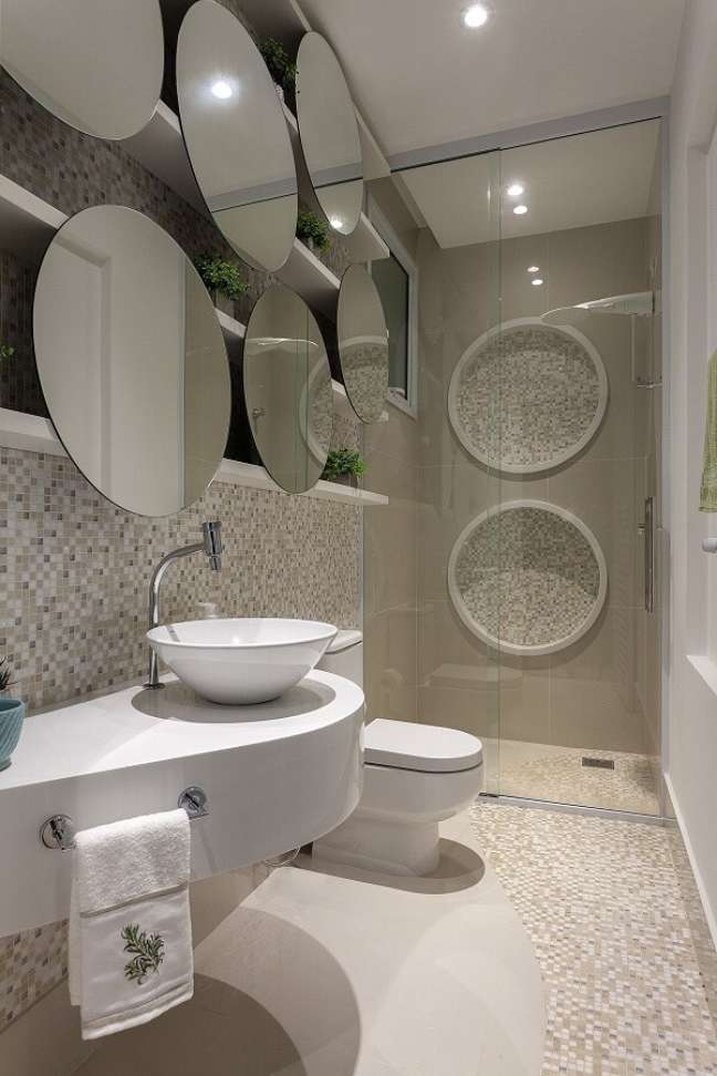 2. Banheiro bege com bancada branca moderna e espelho redondo – Foto Iara Kilaris