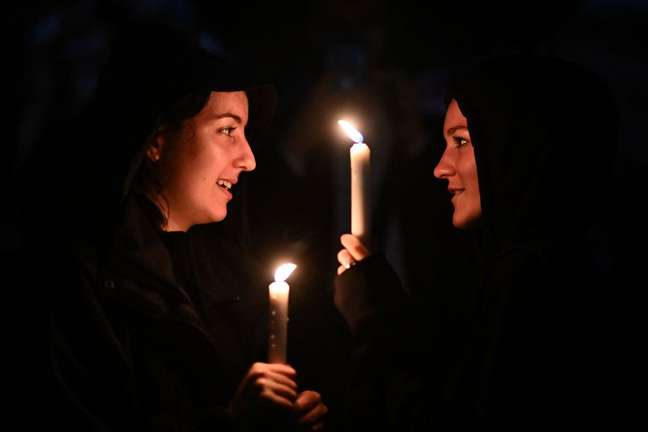 Mulheres seguram vela em frente ao palácio de Buckingham