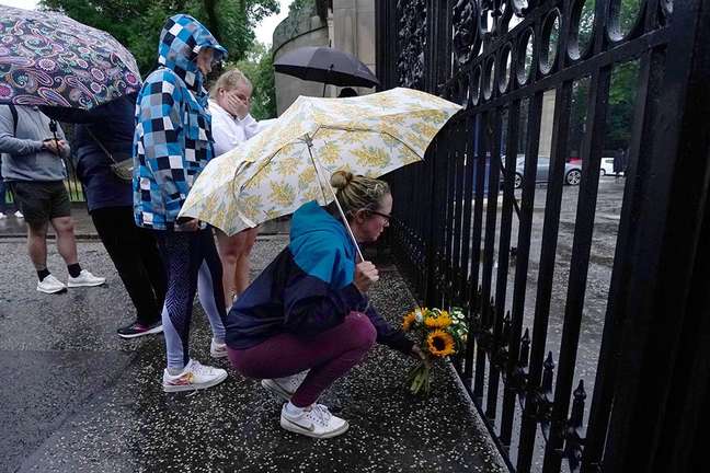 Mulher deposita flores em frente ao Palácio de Holyroodhouse, em Edimburgo