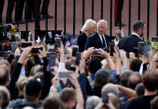 Rei Charles e Camilla Parker Bowles cumprimentam pessoas em frente ao Palácio de Buckingham  